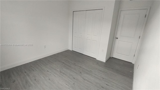 unfurnished bedroom featuring a closet and dark wood-type flooring