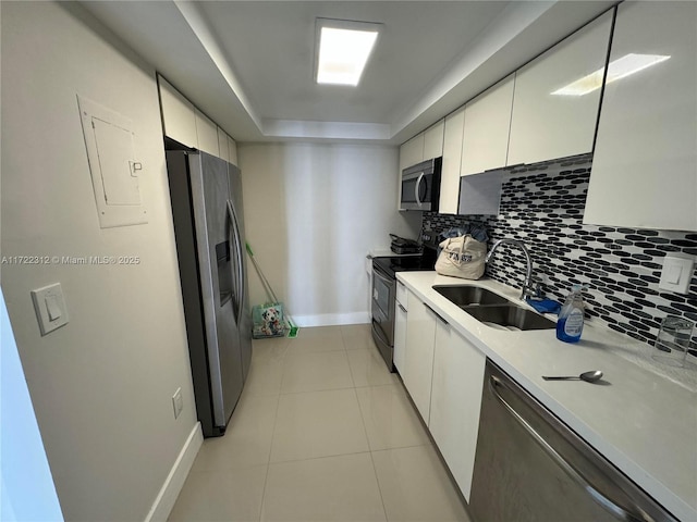 kitchen featuring white cabinets, a raised ceiling, sink, tasteful backsplash, and stainless steel appliances