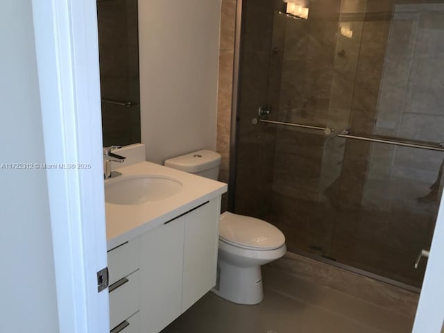 bathroom featuring vanity, toilet, and a shower with shower door