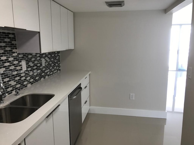 kitchen featuring dishwasher, sink, white cabinetry, and backsplash