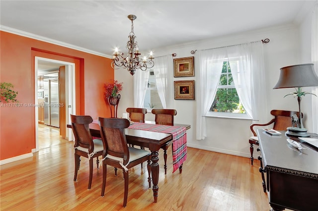 dining area with a chandelier, crown molding, and light hardwood / wood-style flooring