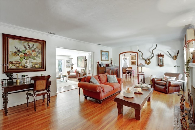 living room with light wood-type flooring, crown molding, and a notable chandelier