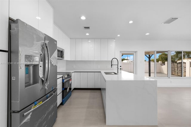 kitchen with white cabinets, decorative backsplash, sink, and stainless steel appliances