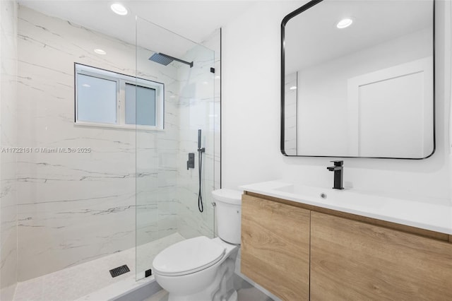 bathroom with tiled shower, vanity, and toilet