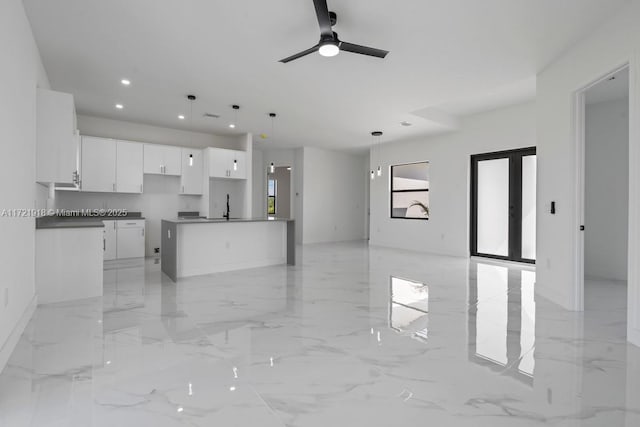 kitchen featuring open floor plan, marble finish floor, white cabinetry, a sink, and recessed lighting