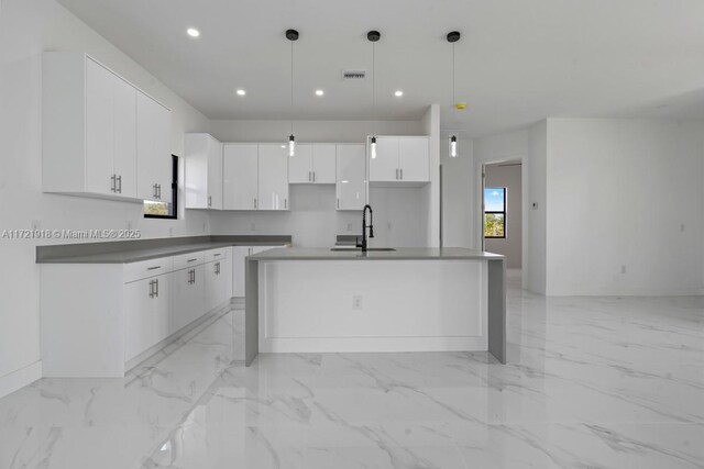 kitchen with a center island, white cabinets, hanging light fixtures, and sink