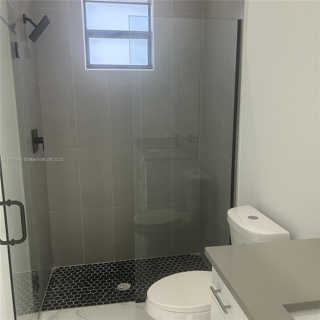 bathroom with a shower with door, vanity, and toilet