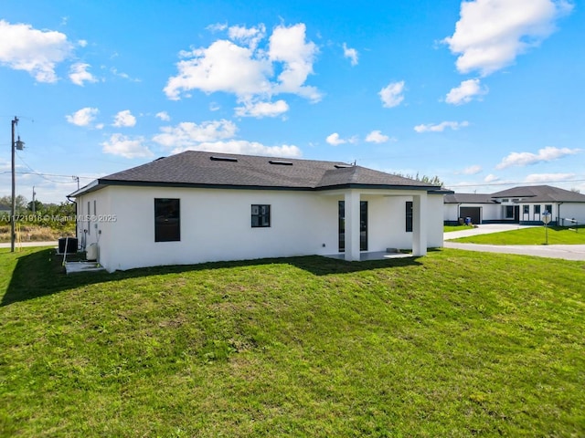 1608 Flora Ave S, Lehigh Acres, FL 33976 - back of property featuring roof with shingles, cooling unit, a lawn, and stucco siding