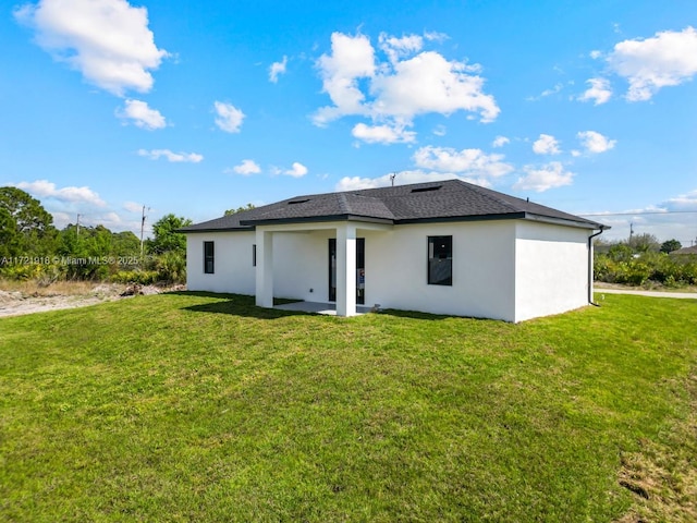 1608 Flora Ave S, Lehigh Acres, FL 33976 - rear view of house featuring stucco siding, roof with shingles, a patio, and a yard