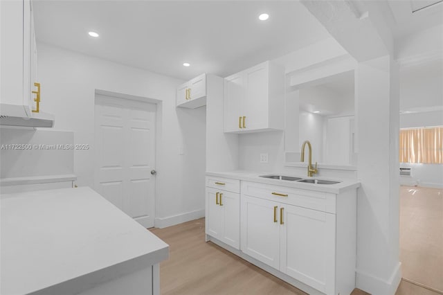 kitchen featuring sink, white cabinets, and light wood-type flooring