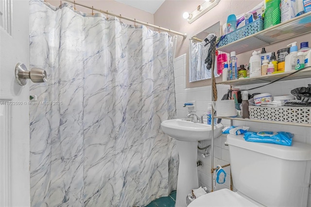 bathroom featuring toilet, tile walls, curtained shower, and sink