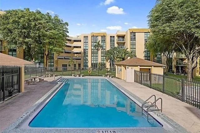 community pool with fence and a patio area