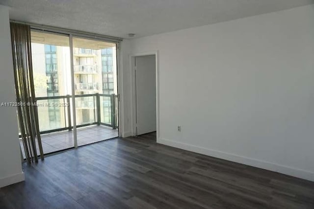 spare room with dark wood-style flooring, baseboards, and expansive windows