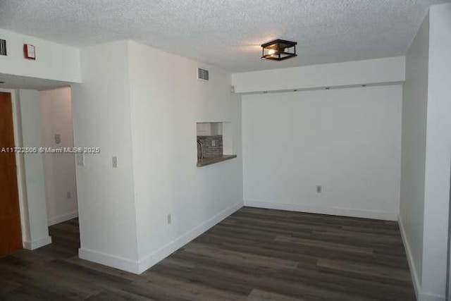 empty room featuring baseboards, a textured ceiling, visible vents, and wood finished floors