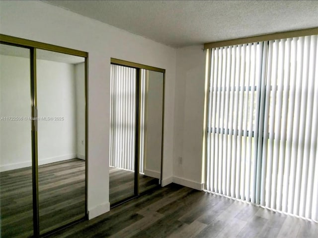 unfurnished bedroom with multiple closets, baseboards, and wood finished floors