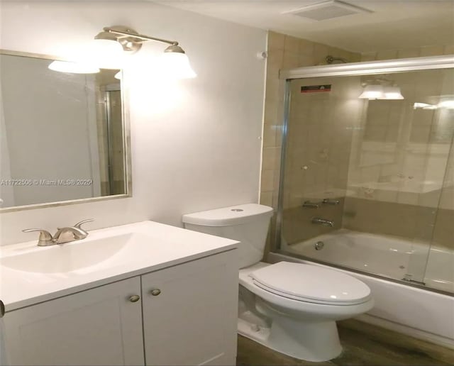 bathroom with vanity, enclosed tub / shower combo, visible vents, and toilet