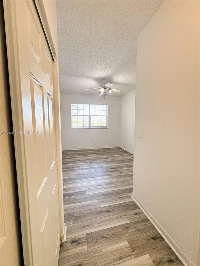 spare room with ceiling fan, light wood-type flooring, and a textured ceiling