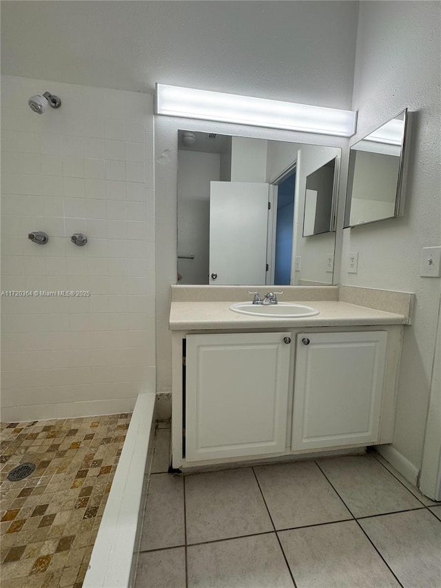 bathroom featuring tile patterned floors, vanity, and a tile shower