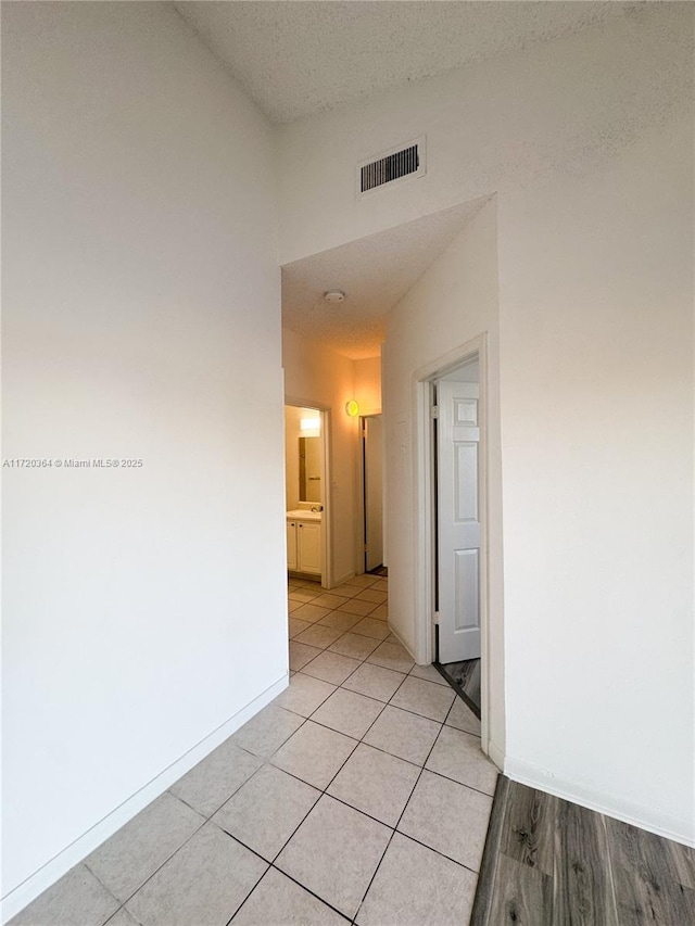 hallway featuring light tile patterned floors and a textured ceiling