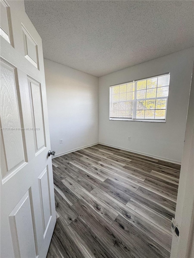 spare room featuring dark hardwood / wood-style flooring and a textured ceiling