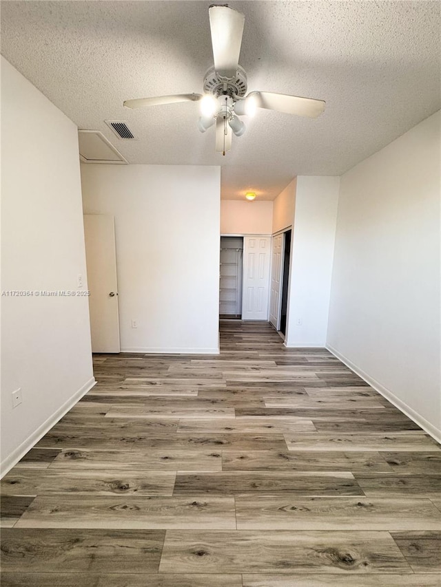 empty room with ceiling fan, a textured ceiling, and hardwood / wood-style flooring