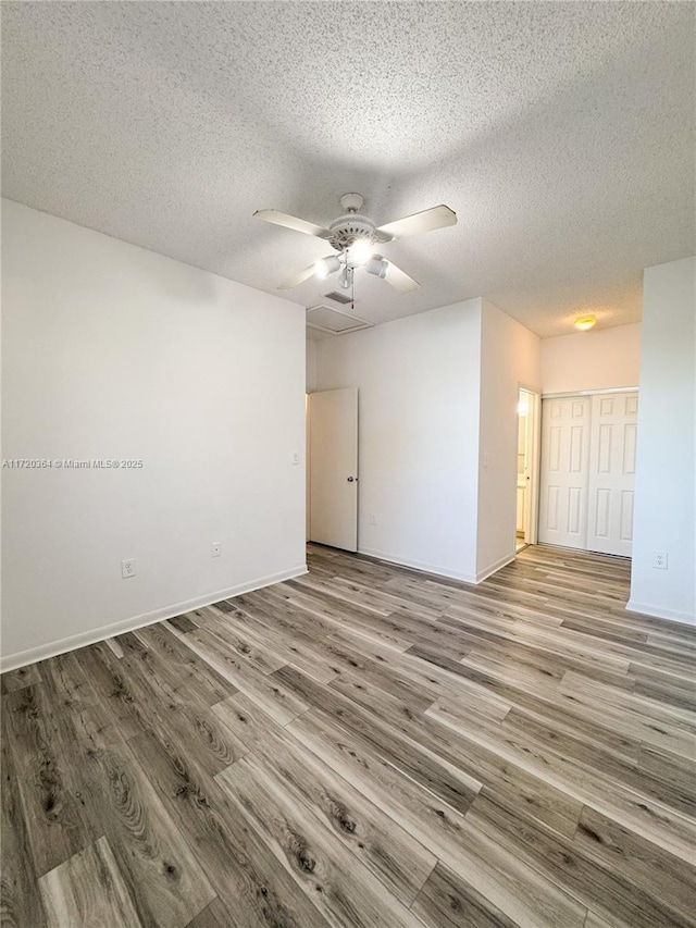 empty room featuring ceiling fan, a textured ceiling, and light hardwood / wood-style flooring