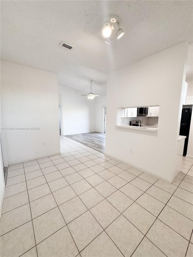 spare room with light tile patterned floors, a textured ceiling, and ceiling fan