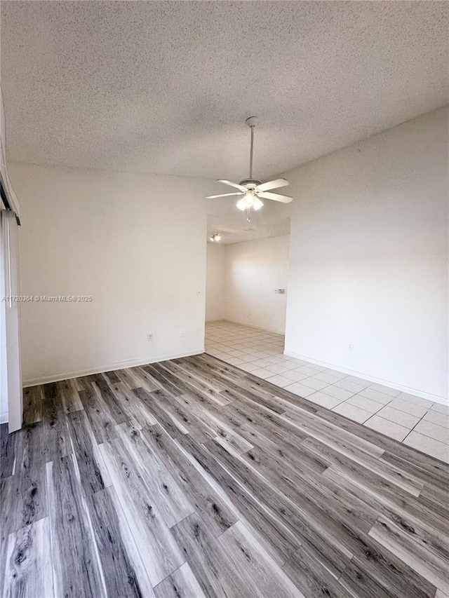 unfurnished room featuring ceiling fan, light hardwood / wood-style floors, and a textured ceiling