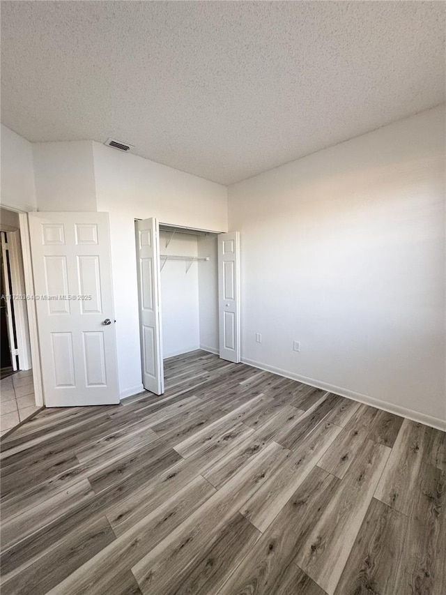 unfurnished bedroom with dark hardwood / wood-style flooring, a textured ceiling, and a closet