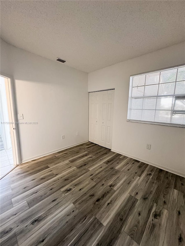 unfurnished bedroom featuring a textured ceiling, a closet, and dark wood-type flooring