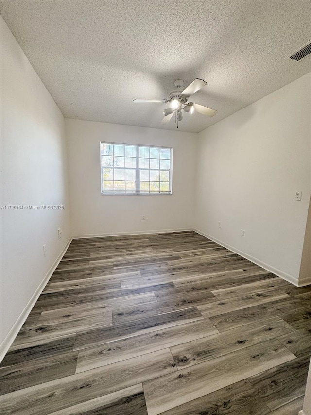 spare room featuring a textured ceiling, ceiling fan, and dark wood-type flooring