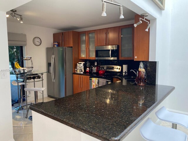 kitchen featuring kitchen peninsula, appliances with stainless steel finishes, decorative backsplash, and a kitchen breakfast bar