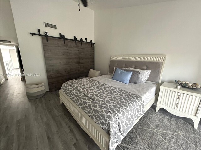 bedroom featuring dark hardwood / wood-style flooring and a barn door