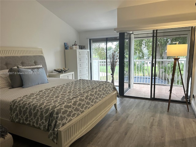 bedroom with access to exterior, hardwood / wood-style flooring, and vaulted ceiling