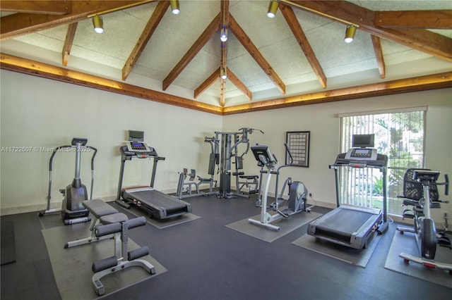 exercise room with beamed ceiling, high vaulted ceiling, and baseboards