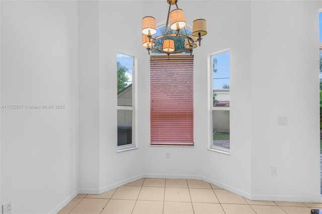 tiled spare room with a chandelier