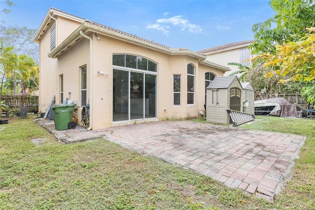 rear view of property with a lawn, a patio, and a shed