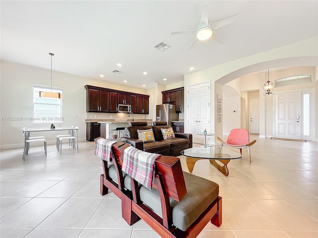 living room featuring ceiling fan with notable chandelier, light tile patterned flooring, and sink