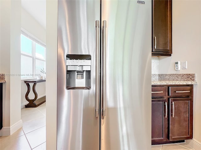 interior details featuring light stone counters, dark brown cabinets, and stainless steel refrigerator with ice dispenser