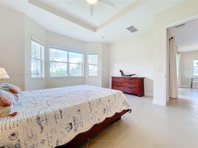 bedroom featuring ceiling fan, light tile patterned floors, and a tray ceiling