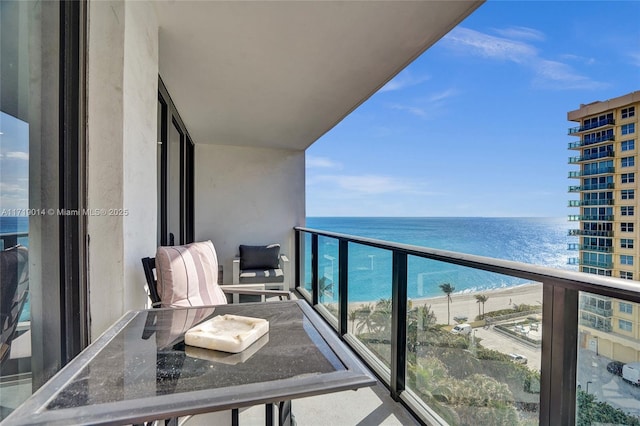 balcony with a water view and a view of the beach