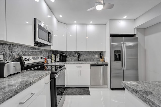 kitchen with light stone countertops, stainless steel appliances, white cabinets, and sink