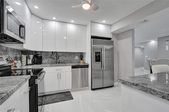 kitchen featuring decorative backsplash, sink, white cabinetry, light stone countertops, and appliances with stainless steel finishes