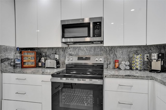 kitchen featuring stainless steel appliances, backsplash, white cabinets, and light stone countertops