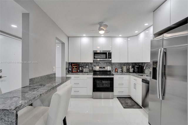 kitchen featuring light stone countertops, white cabinetry, and stainless steel appliances