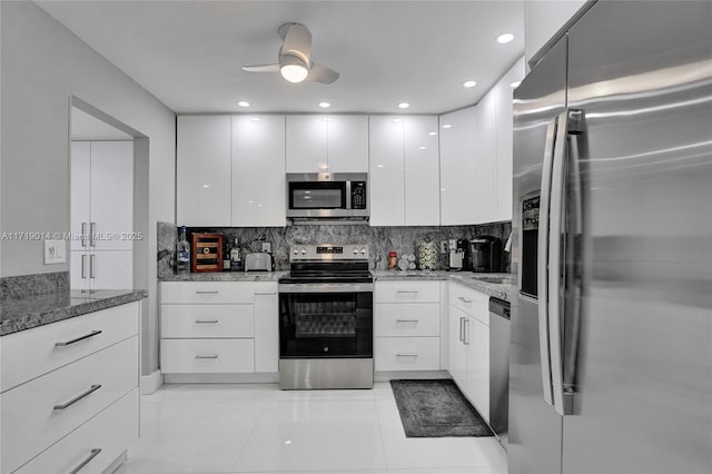 kitchen with ceiling fan, backsplash, stainless steel appliances, white cabinets, and stone countertops