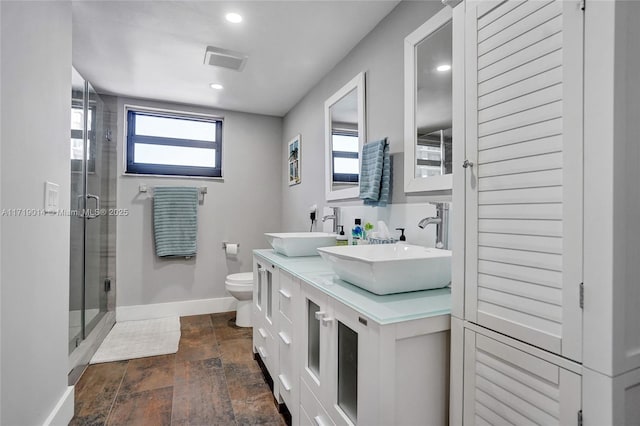 bathroom with toilet, a shower with door, and vanity