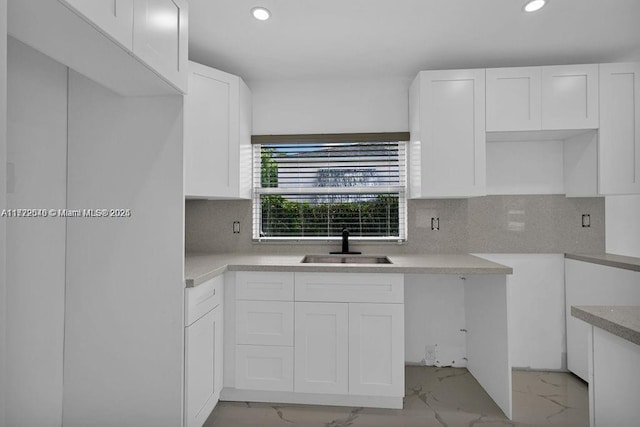 kitchen featuring white cabinets, sink, and tasteful backsplash