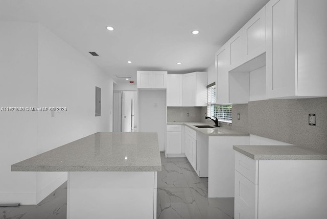 kitchen featuring a center island, electric panel, sink, tasteful backsplash, and white cabinetry