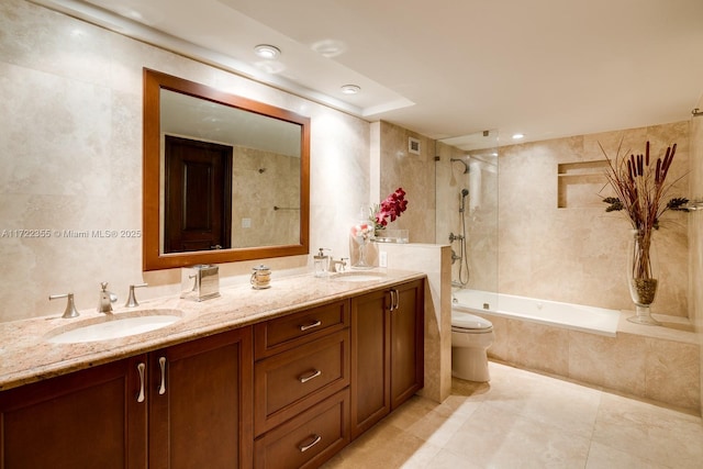 full bathroom featuring vanity, tile patterned flooring, tiled shower / bath combo, toilet, and tile walls